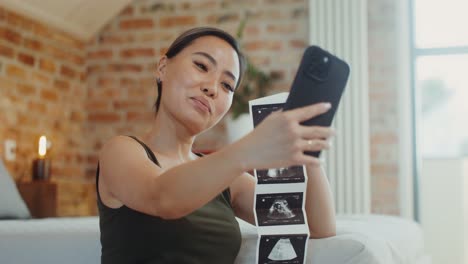 pregnant woman taking a selfie with her ultrasound