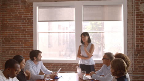 businesswoman standing to address boardroom meeting