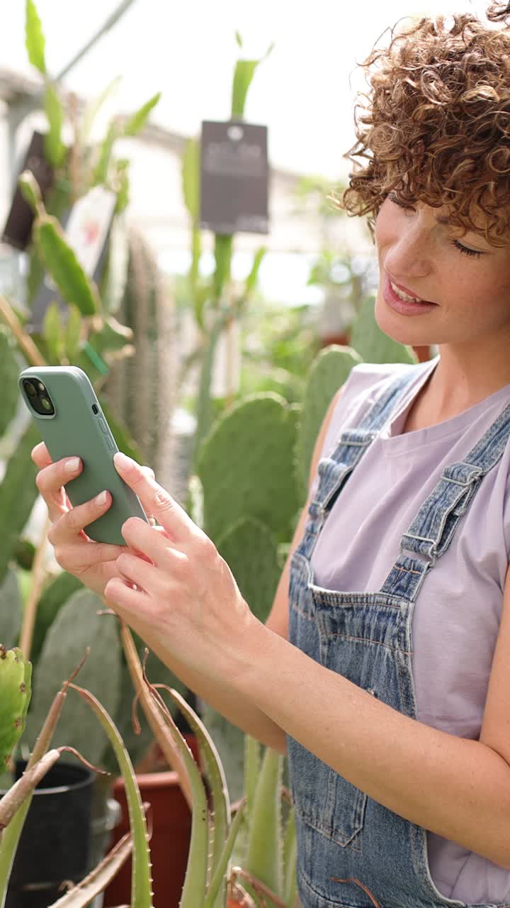 Woman browsing smartphone in greenhouse. Vertical