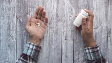 hands holding pills and medicine bottle