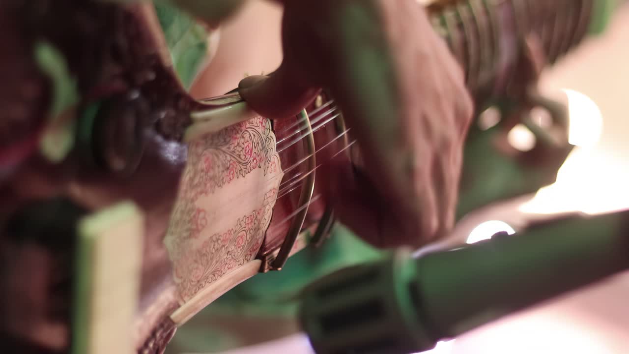 4K Close up of a man playing an Indian Sitar, looking up the neck of the instrument