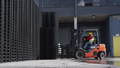 warehouse worker driving forklift outside factory