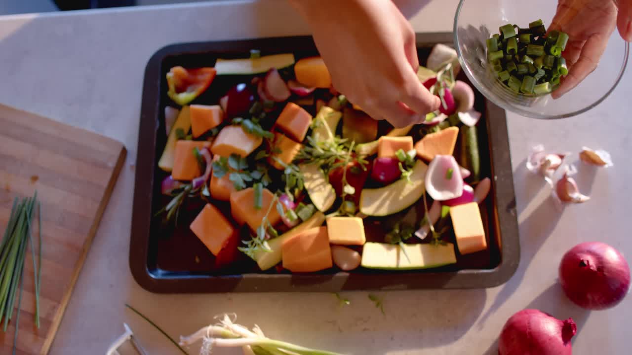 vista aérea de las manos de una mujer afroamericana preparando una comida en una cocina soleada, en cámara lenta