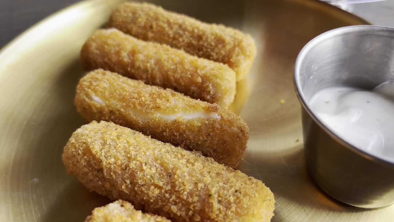 plate of five appetizing mozarella sticks with their sauce in a bowl next to them