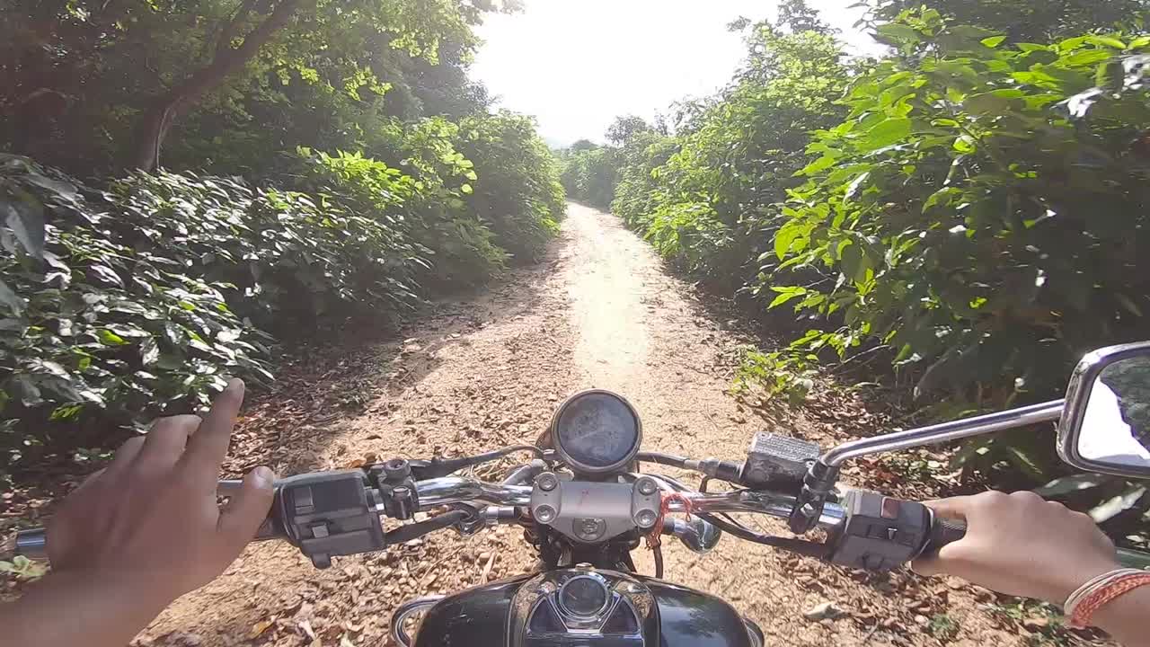 motociclista montando campo a través en un denso callejón verde montando a la montaña en la colina de parasnath en jharkhand, india