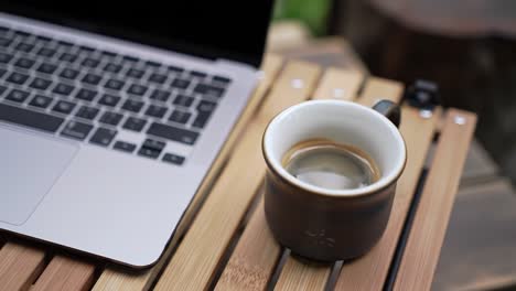 a serene workspace with a laptop and a cup of coffee on a wooden table, capturing a moment of productivity and relaxation in a cozy environment