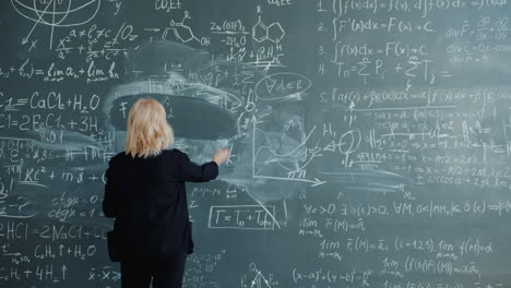 woman writing equations on a chalkboard