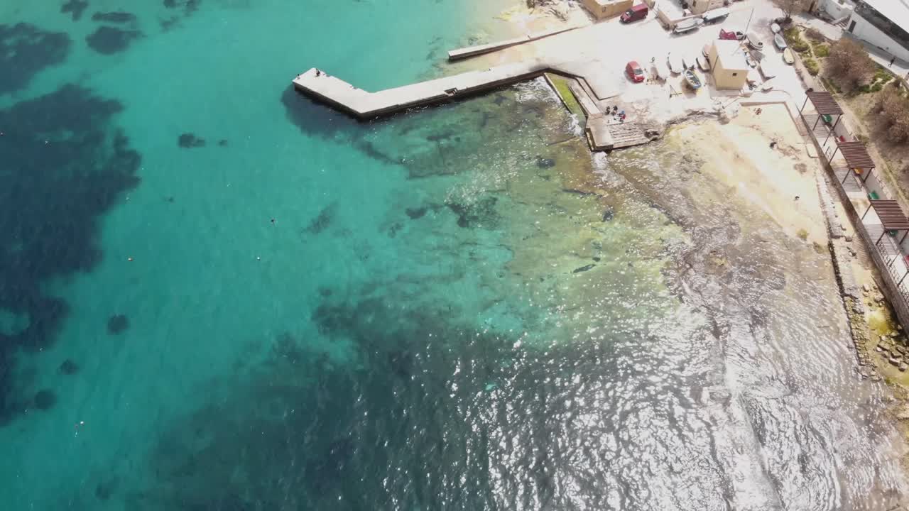vista de pájaro del muelle que se extiende sobre aguas claras del mediterráneo a orillas de sliema, en malta - toma aérea sobrevolada