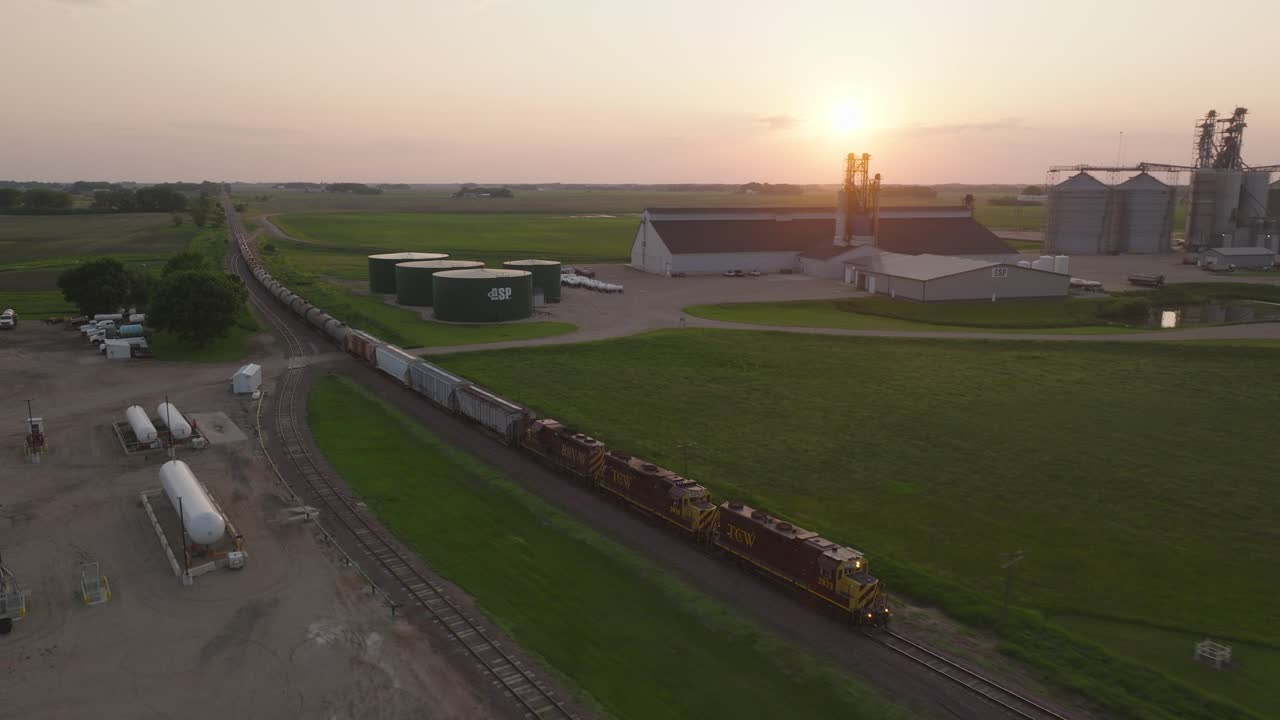 Freight Train Passing Through Countryside And Fertilizer Plant During Sunset. - aerila shot