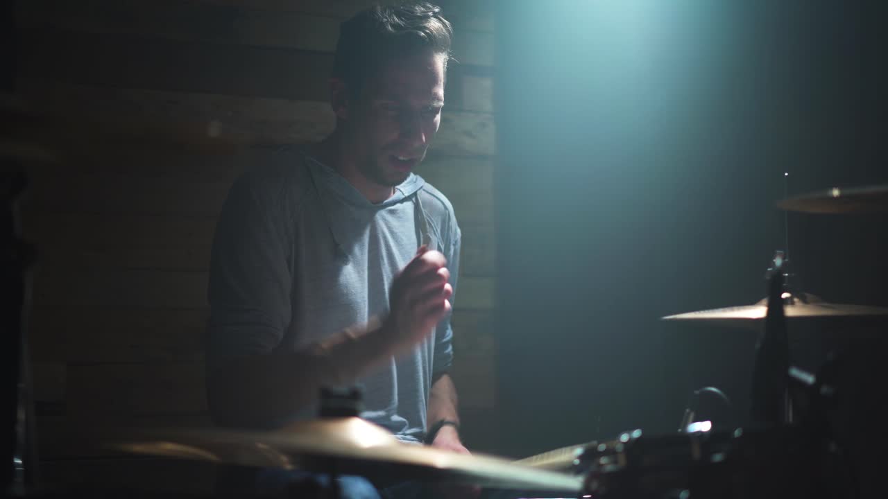 Man drumming with passion and intention; stick flip, tom and cymbal hits.