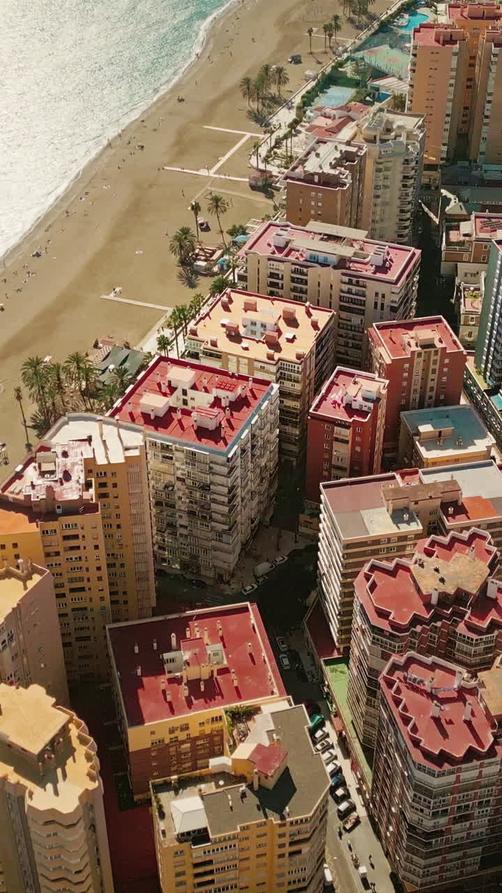 Sorvolo aereo verticale della costa di Malaga, Spagna, con appartamenti a molti piani fronte mare e spiaggia sabbiosa lungo il Mar Mediterraneo