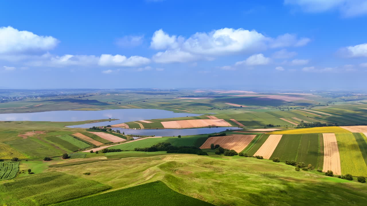 Scenic view of rolling hills and fields near a river. Breathtaking landscape with green fields, a winding river, and clear blue skies on a sunny day in rural countryside
