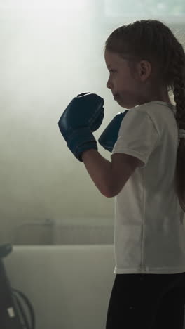 niño golpea almohadillas en sparring con el entrenador en el gimnasio. instructor de boxeo lleva a cabo la batalla con la niña en la escuela de deportes en cámara lenta. actividad física