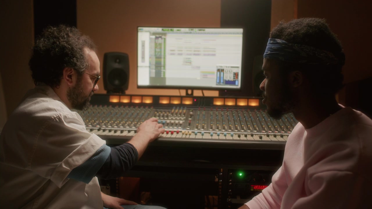 Multiethnic Audio Engineer and Musician Talking and Using Studio Mixing Desk