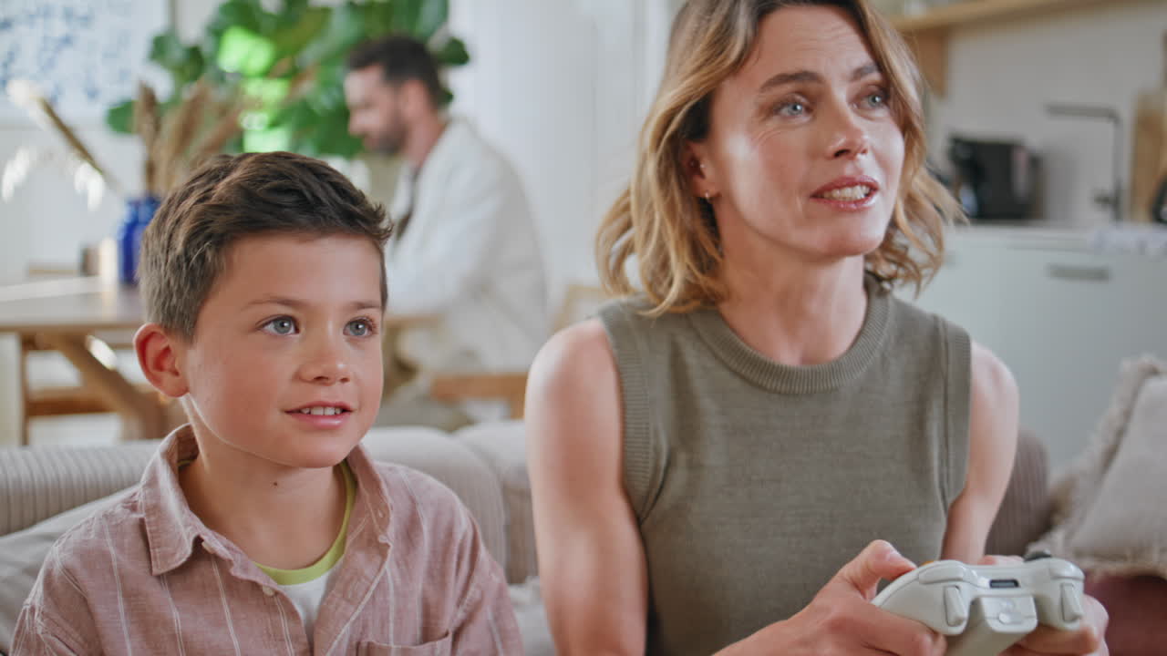 Mother son gaming console at morning home closeup. Cheerful mom child playing