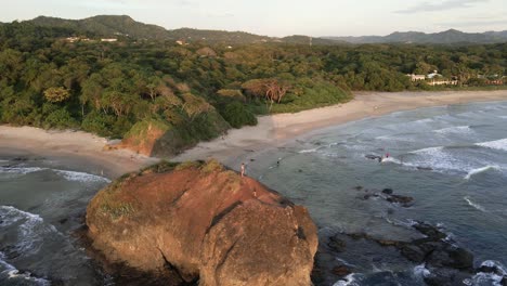 father and son standing on a large beach rock at playa grande near tamarindo, costa rica
