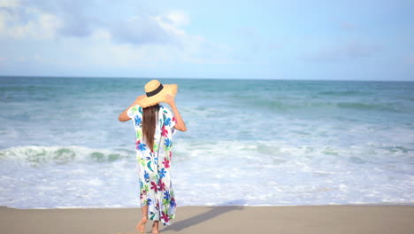 Back-view-of-woman-on-seashore-raising-arms-and-looking-at-horizon