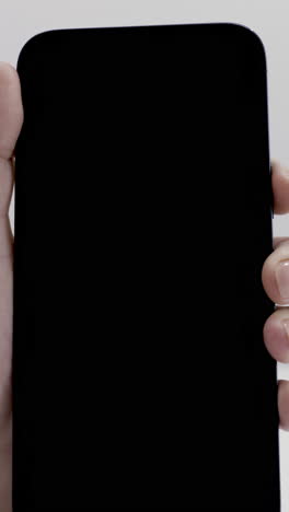 hand holding a smartphone with black screen