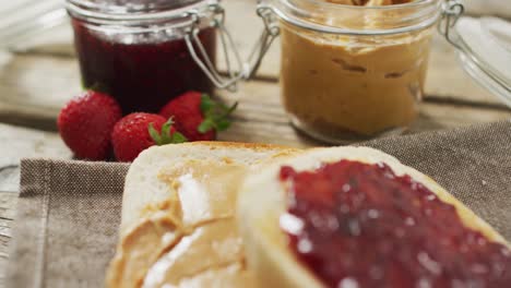 sándwich de mantequilla de maní y jalea en una bandeja de madera con fresas en una superficie de madera