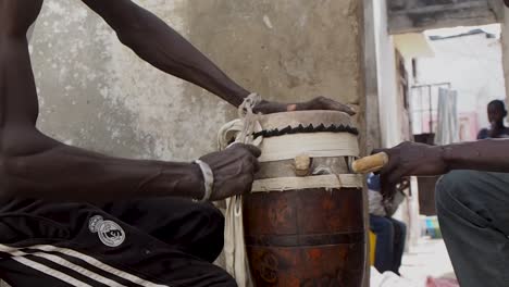 wide shot of senegalese man skinning a sabar