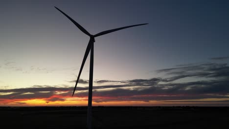 Silueta-De-Turbina-Eólica-Giratoria-En-El-Campo-Agrícola-Durante-La-Puesta-De-Sol-Dorada