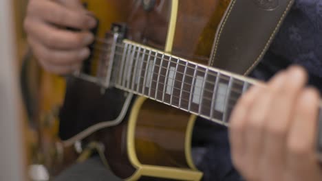 Primer-Plano-De-Un-Músico-Profesional-Tocando-Un-Solo-En-Una-Guitarra-Eléctrica-De-Cuerpo-Hueco-Con-Una-Púa-De-Guitarra-Durante-Una-Sesión-De-Grabación-En-Un-Estudio-Con-Un-Fondo-Borroso