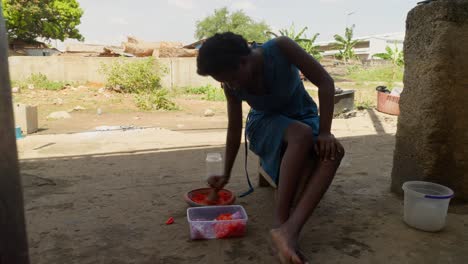 woman grinding pepper with mortar, part of ghanas traditional dish, banku