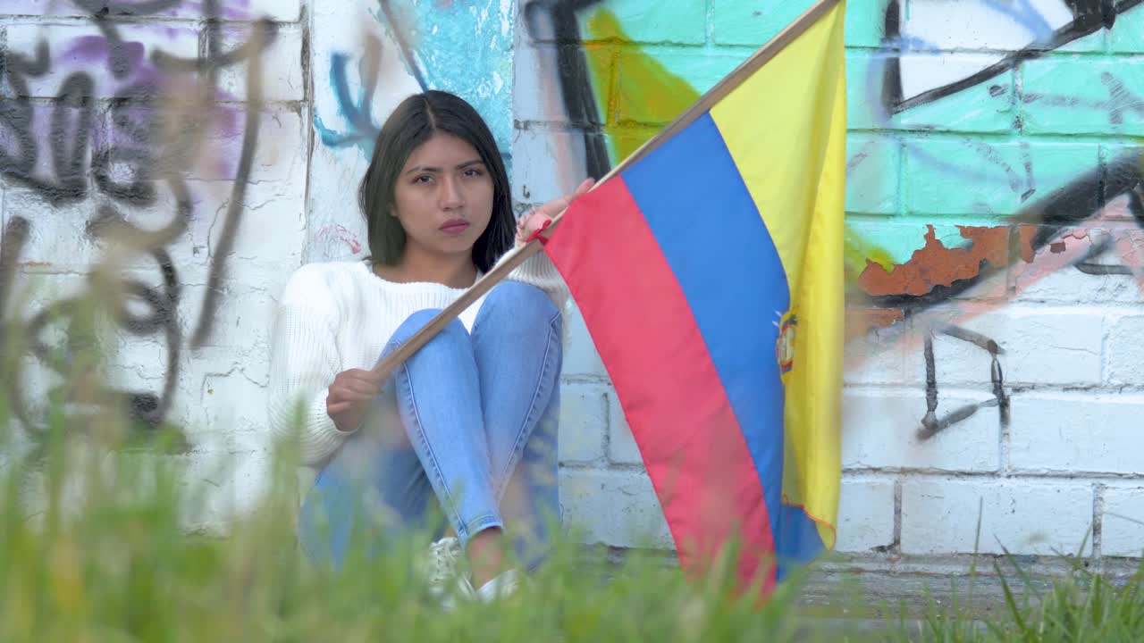 una triste mujer latinoamericana con esperanza sosteniendo la bandera de ecuador cerca de la pared de graffiti