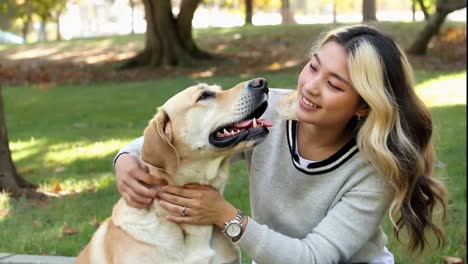 happy young asian woman hugging her adorable labrador retriever dog outdoors.