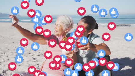 Heart-and-like-icons-floating-against-senior-couple-holding-drinks-taking-a-selfie-on-the-beach