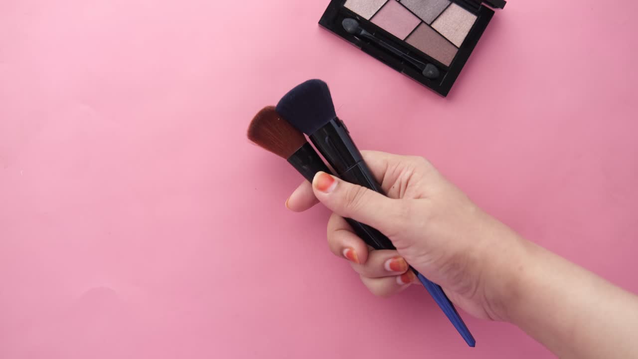 Woman holding makeup brushes with eyeshadow palette