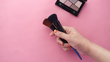 woman holding makeup brushes with eyeshadow palette