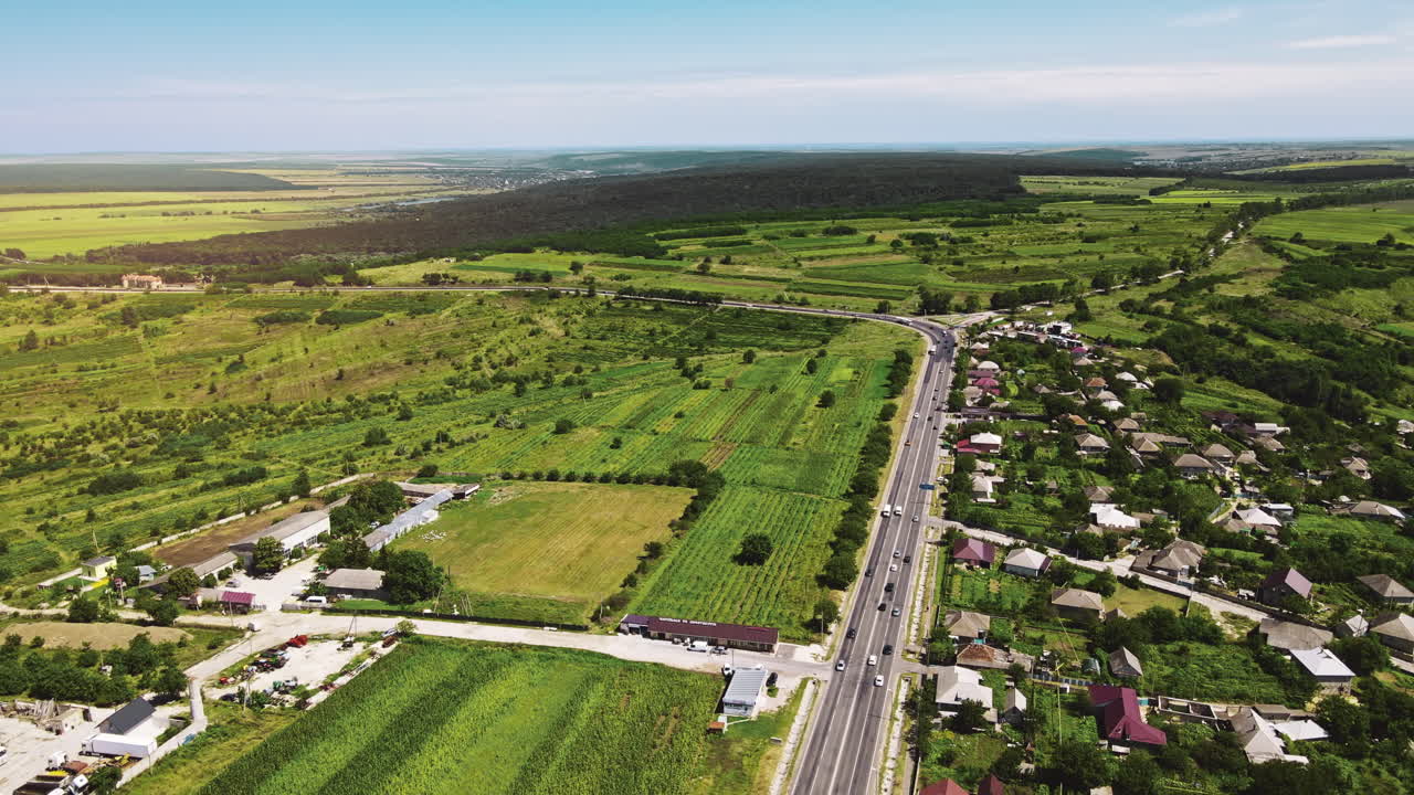 Aerial drone view of a village and road with cars. Greenery, hills and fields in Moldova