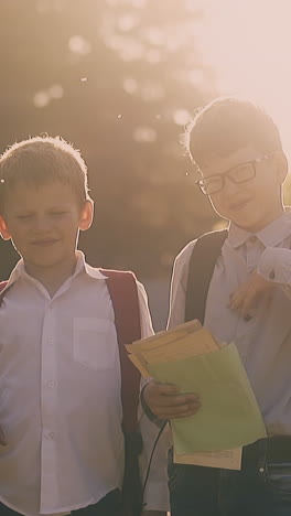 kids in school uniform with bags hold books and paper sheets wave hands to repel mosquitoes at back sunlight slow motion