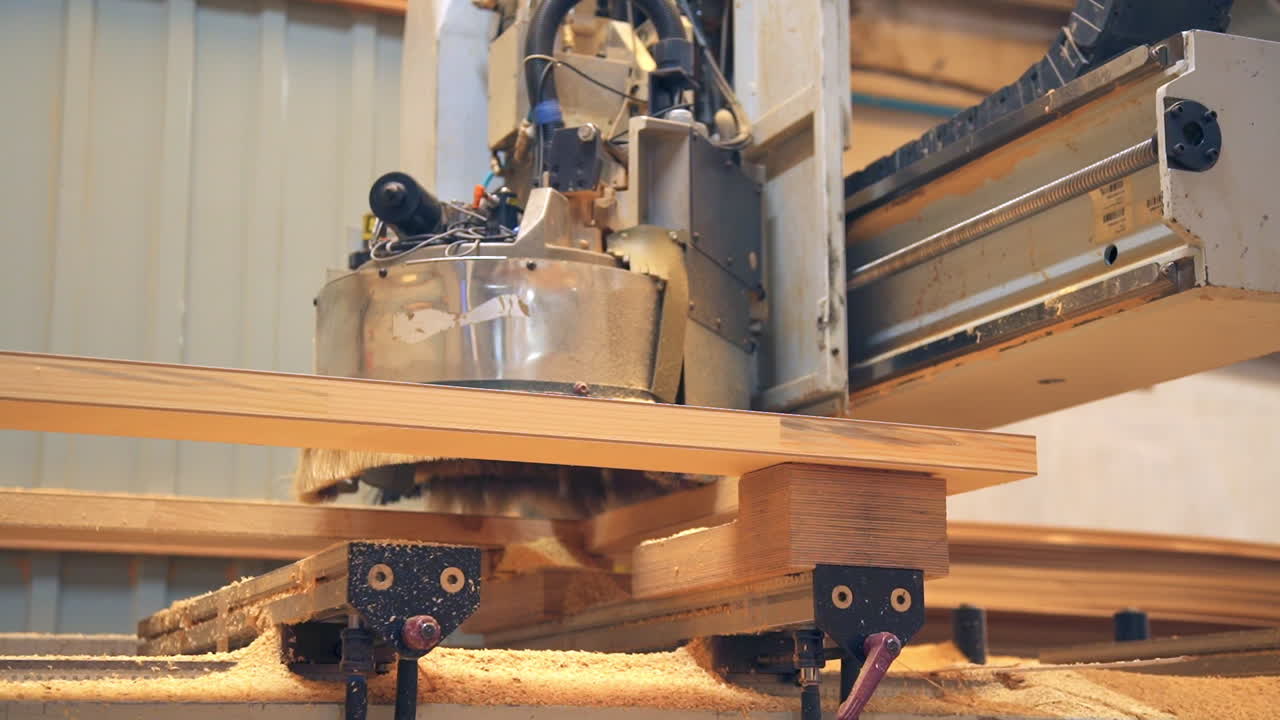 Machine tool moves along the door billet. Chipping out the parts for future wooden door. Low angle view.