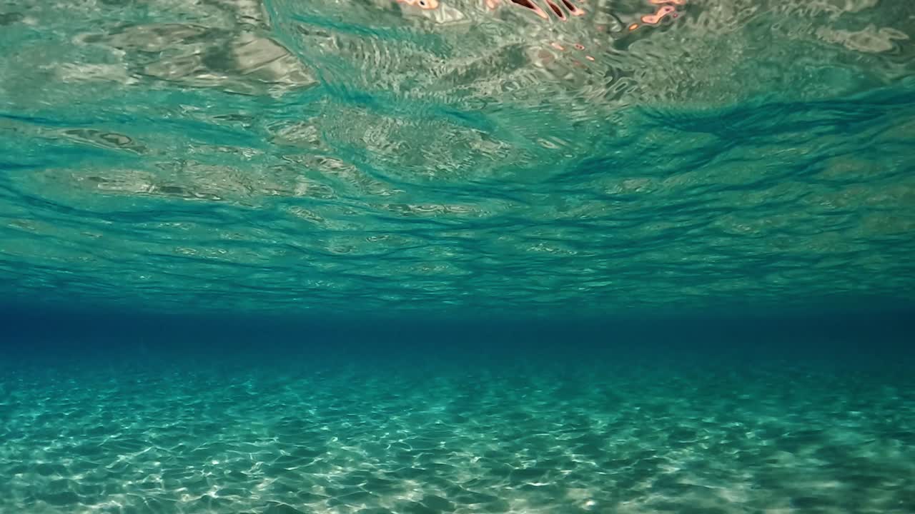 impresionante escena bajo el agua de aguas turquesas cristalinas del océano tropical con superficie ondulada y reflejos en el fondo marino con fondo azul.