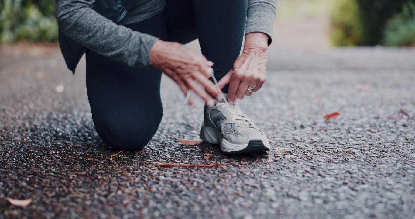 Donna anziana attiva che allaccia le scarpe prima di correre all'aperto