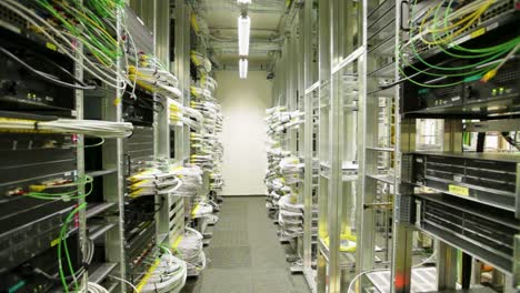 Many-white-wires-connected-to-servers-in-a-datacenter,-wide-shot,-slide-right