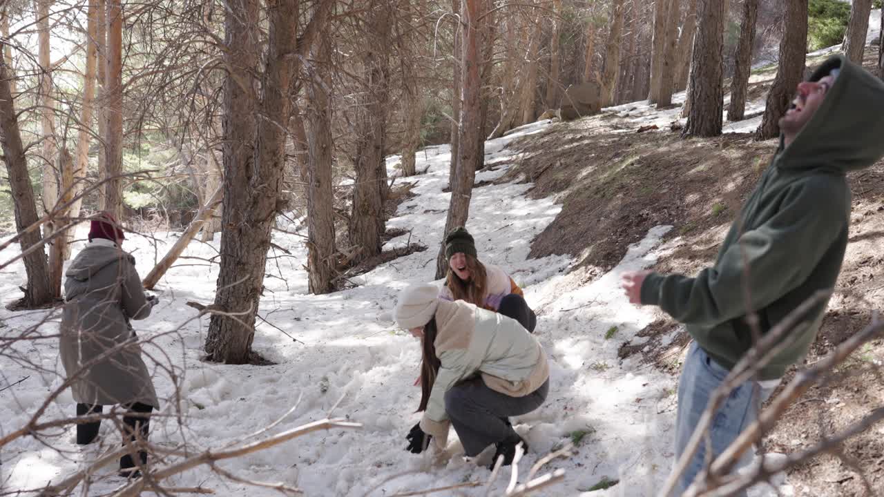 Friends having a snowball fight in the forest