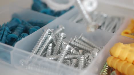 tornillos variados y anclajes de pared en una caja de almacenamiento de plástico