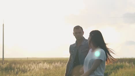 chica en camiseta camina por el campo amarillo sosteniendo la mano del hombre
