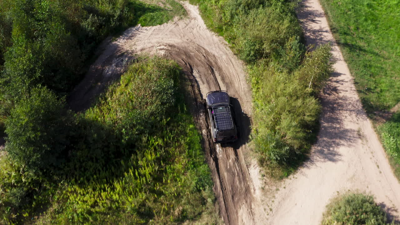 Tracking drone shot of SUV riding on a road in a forest in the day