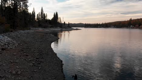 Aerial-shot-of-rocky-shoreline-on-lake-before-sunset