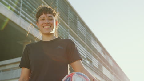 retrato de una chica alegre con una pelota de fútbol al aire libre en un día soleado