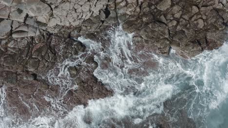 Top-shot-of-a-drone-waves-splashing-on-the-coast-of-an-ocean