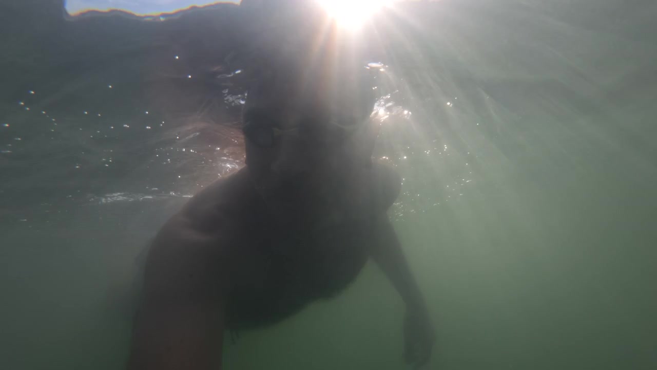 Undervandssilhuet af en mand der snorkler i havet med solstråler, Golfe-Juan, Frankrig