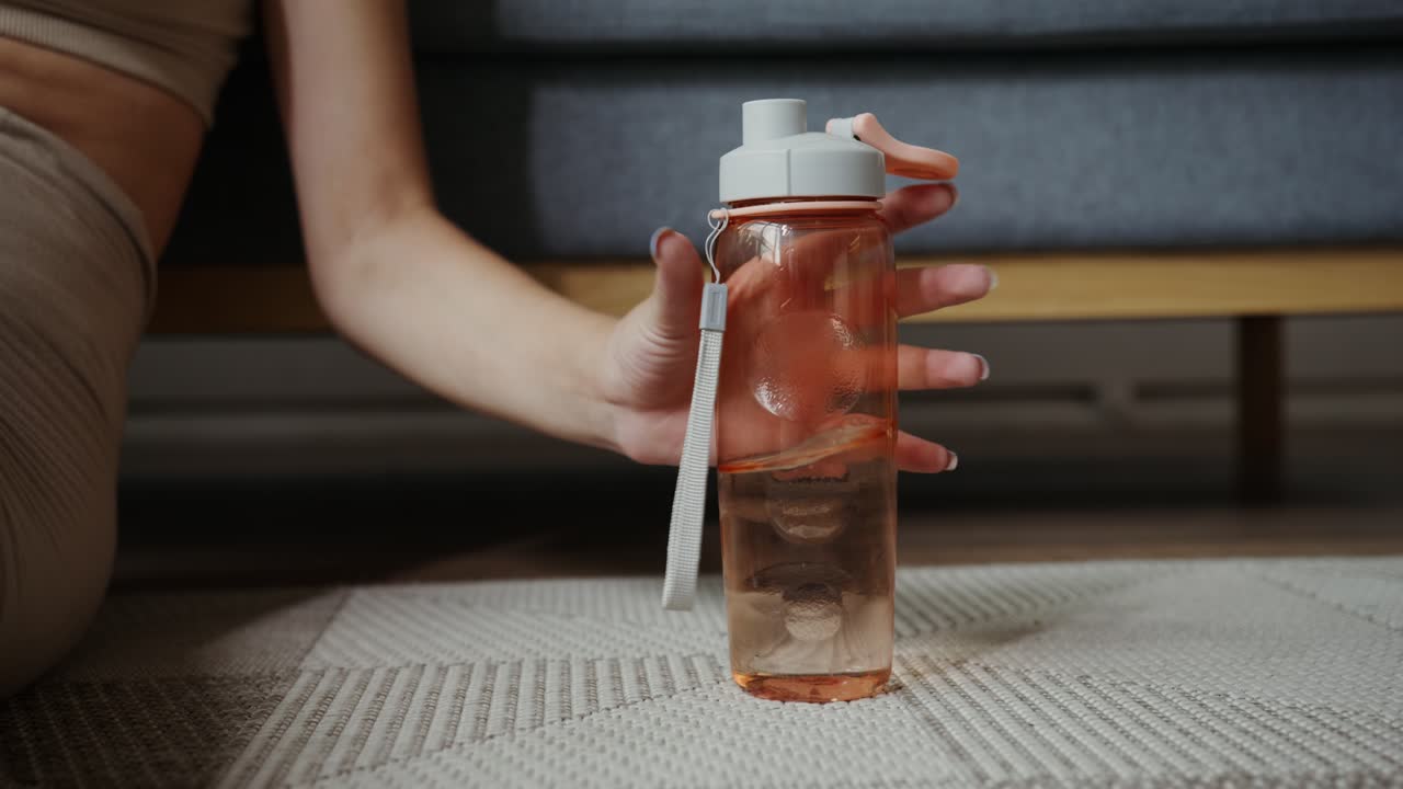 Donna che prende una bottiglia d'acqua dopo un allenamento