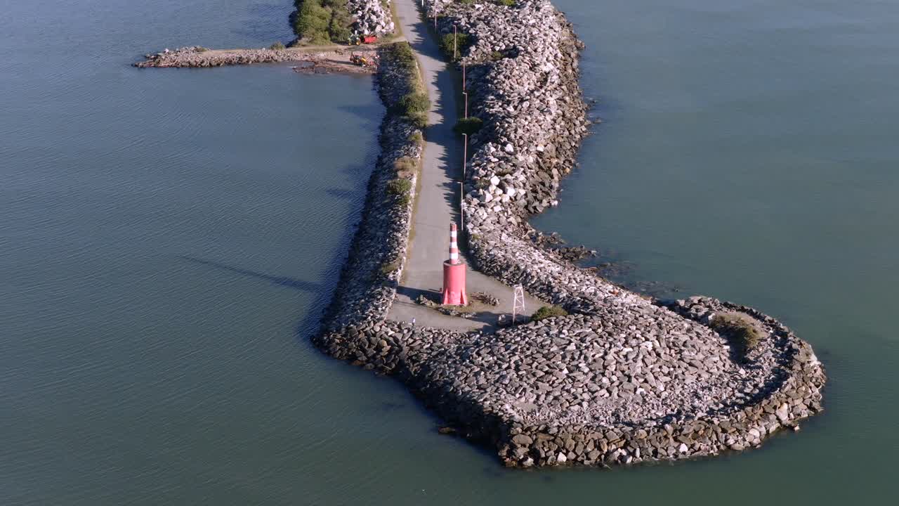 Approaching drone fly to the Farol da Barra breakwater and visitor's viewpoint with lighthouse, Itajaí, Santa Catarina, Brazil