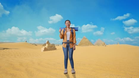 full body of asian female hiker with mountaineering backpack smiling and showing thumbs up gesture to camera while traveling in pyramid of giza