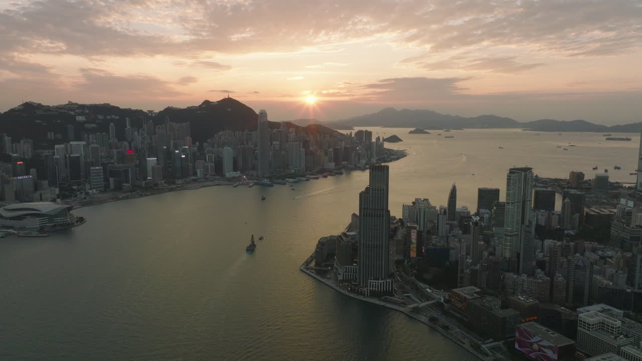 Aerial drone shot of Tsim Sha Tsui district with Rosewood Hotel, K11 in the foreground and Hong Kong Island in the background during sunset